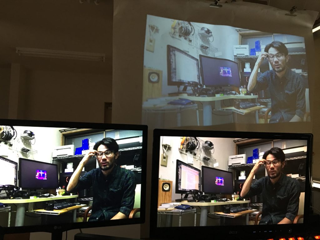 PCモニタ2台の奥に小型プロジェクタ用のスクリーンを設置して3画面にしている様子